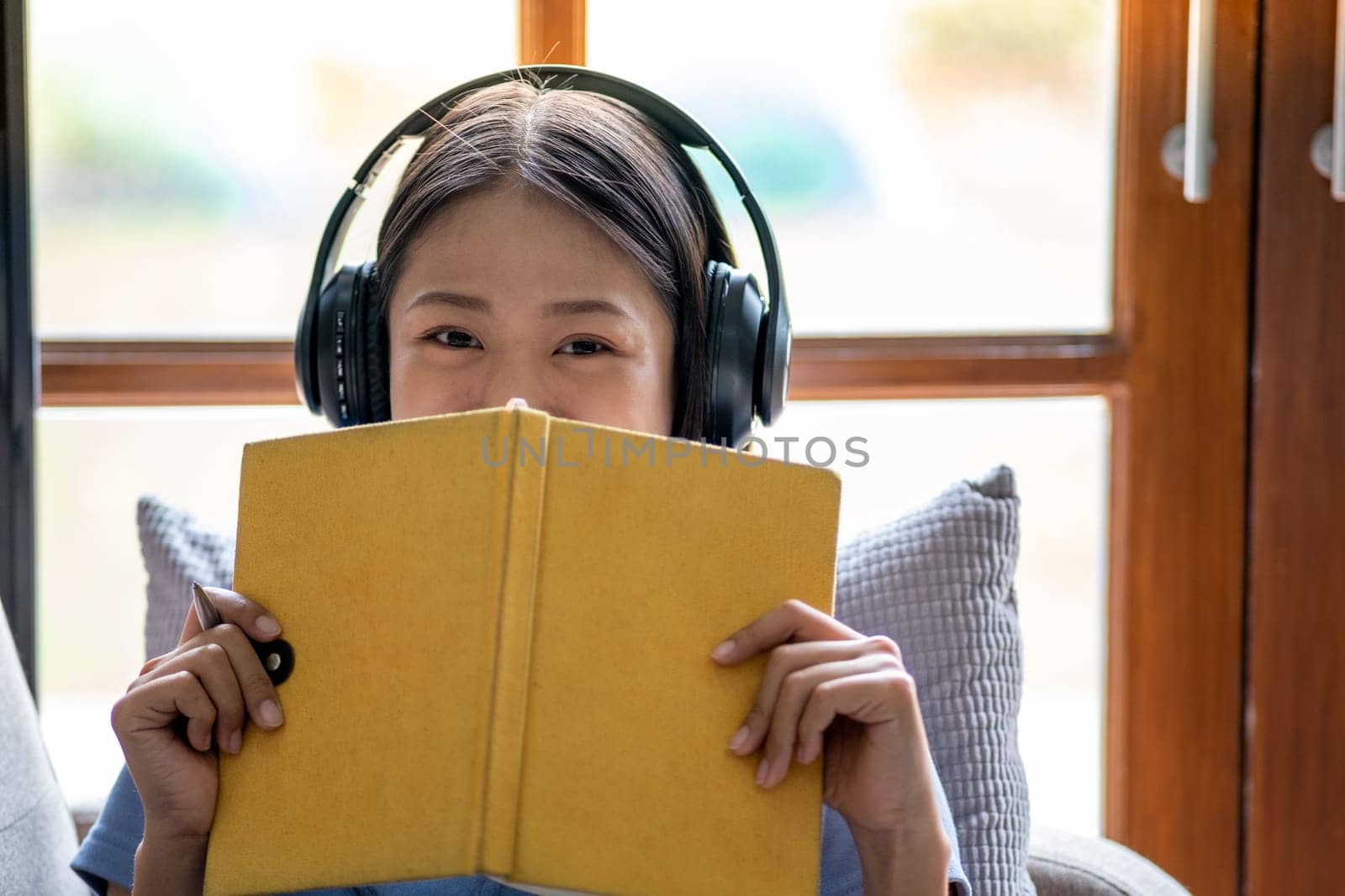 Portrait of young beautiful teenager happy funny Asian woman holding a book and listen the music, relaxing cute Asian chilling at home. High quality photo