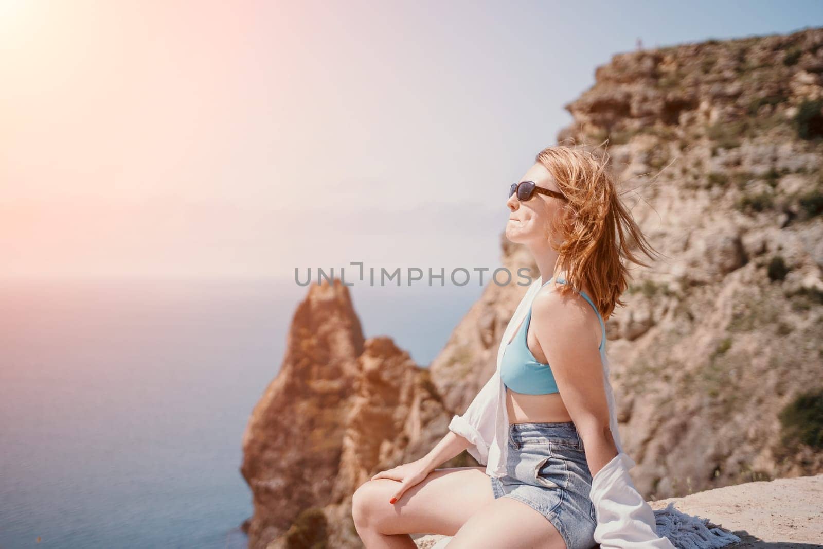 Woman travel sea. Young Happy woman in a long red dress posing on a beach near the sea on background of volcanic rocks, like in Iceland, sharing travel adventure journey