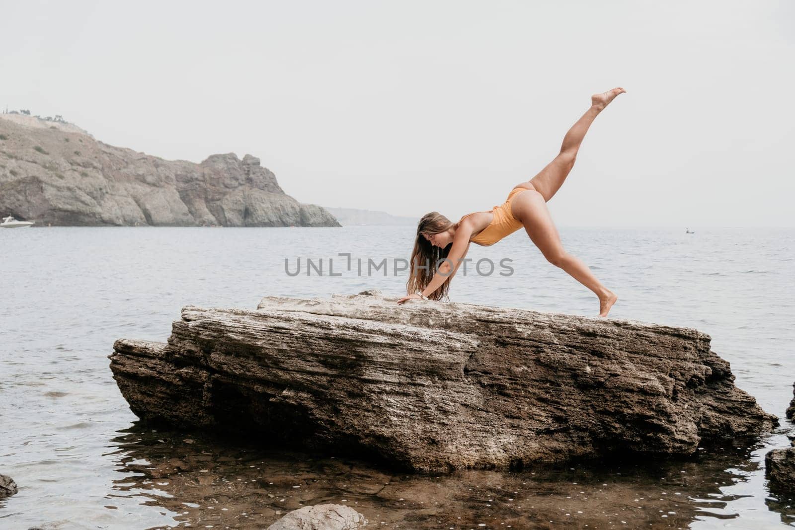 Woman meditating in yoga pose silhouette at the ocean, beach and rock mountains. Motivation and inspirational fit and exercising. Healthy lifestyle outdoors in nature, fitness concept.