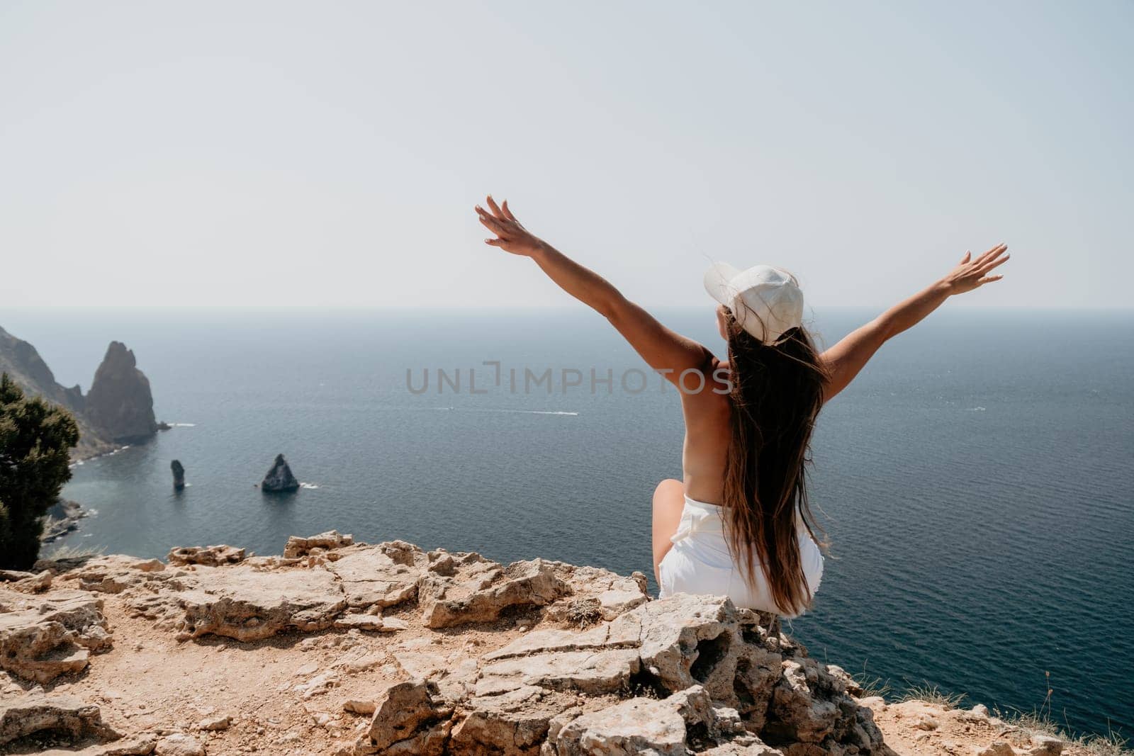 Woman travel sea. Young Happy woman in a long red dress posing on a beach near the sea on background of volcanic rocks, like in Iceland, sharing travel adventure journey