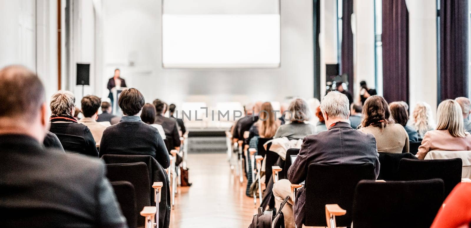 Speaker giving a talk in conference hall at business event. Rear view of unrecognizable people in audience at the conference hall. Business and entrepreneurship concept