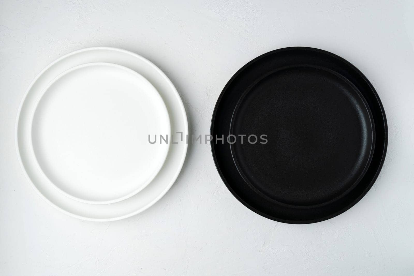 White and black food is an empty ceramic dish on a concrete background. Top View