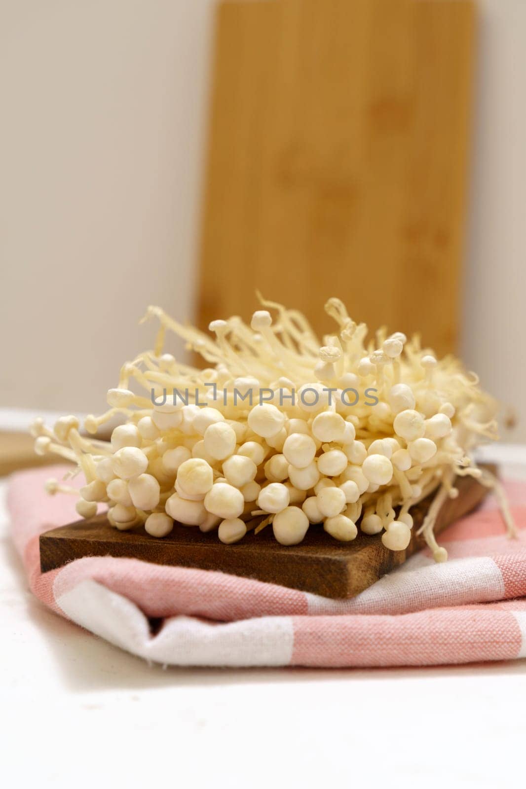 Enoki Flammulina velutipes white mushroom used i food and salads. Vertical photo