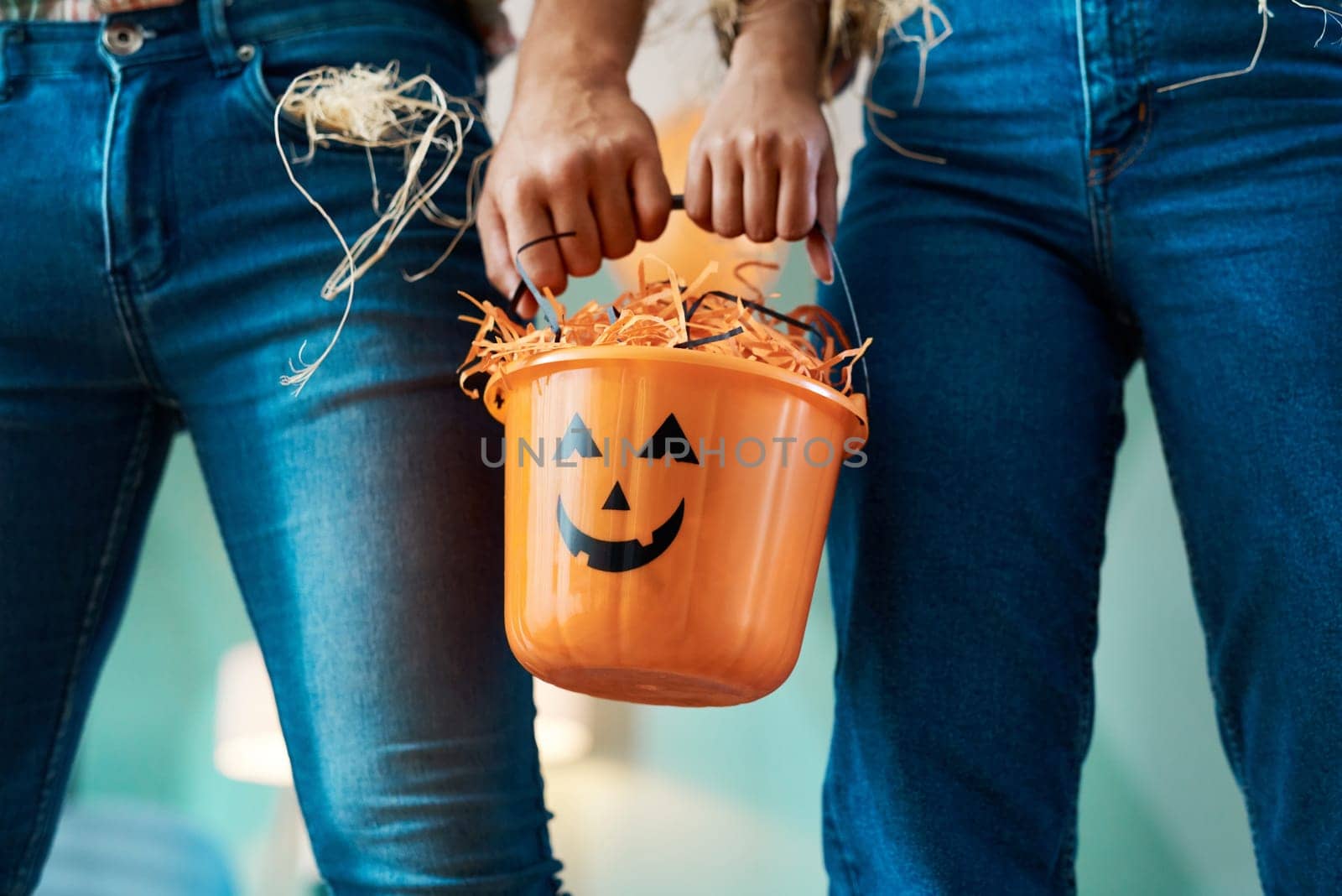 Trick-or-treating together means we get more candy. two unrecognizable people holding a bucket at home