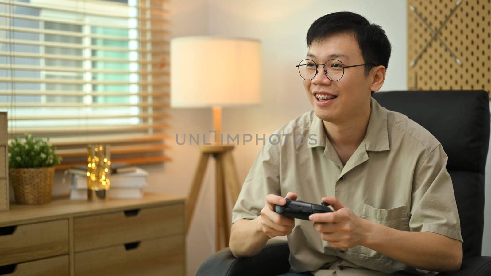 Happy man holding wireless controller playing video game. Entertainment, technology and hobby concept by prathanchorruangsak