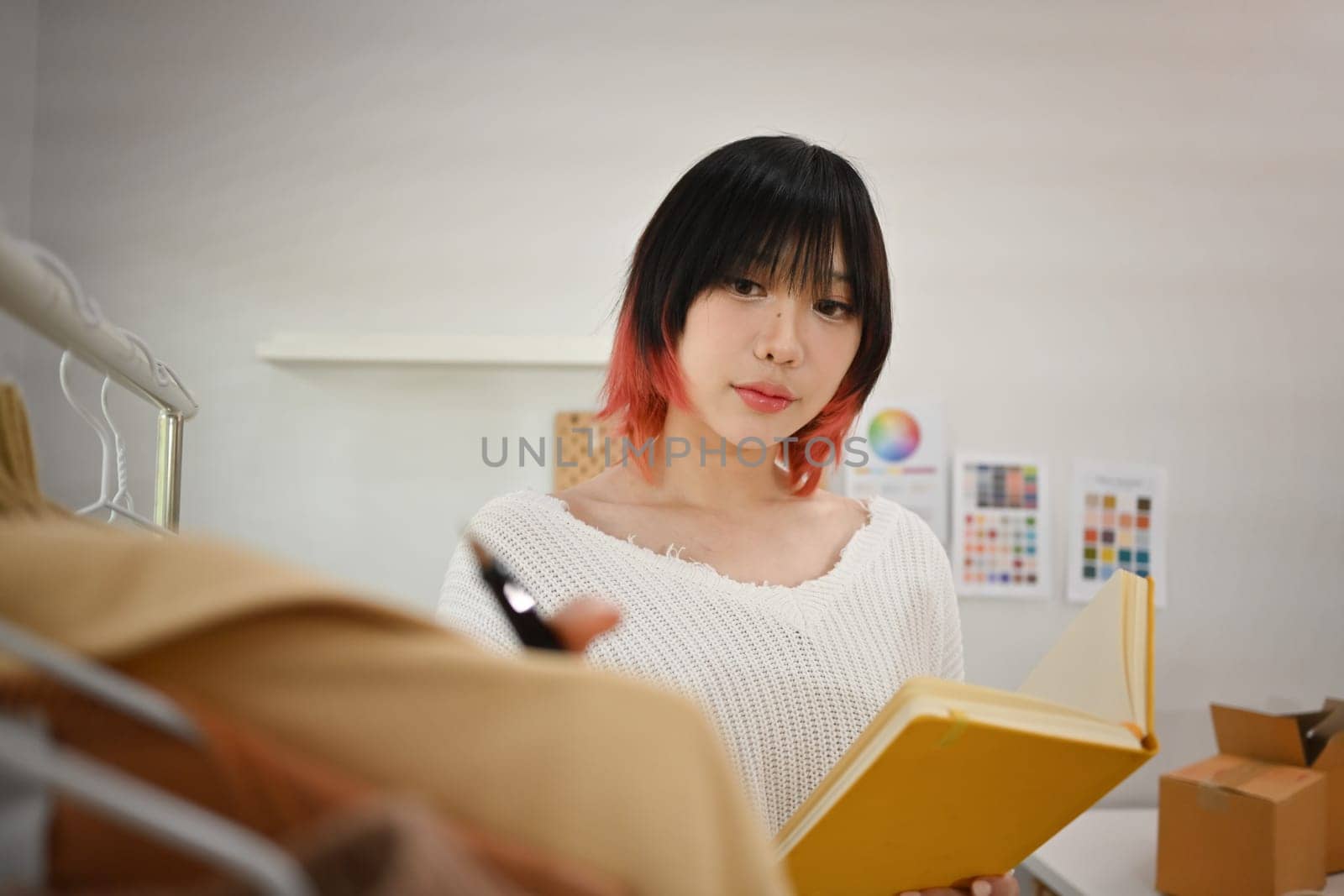 Portrait of young beautiful woman fashion designer working with fabrics at fashion studio.