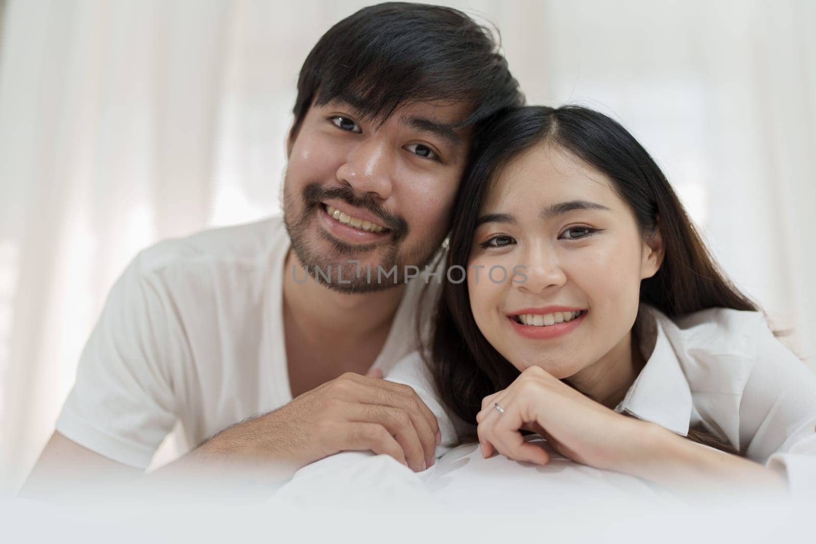 Asian Romantic couple in bed enjoying sensual foreplay Happy sensual young couple lying in bed together. Beautiful loving couple kissing in bed