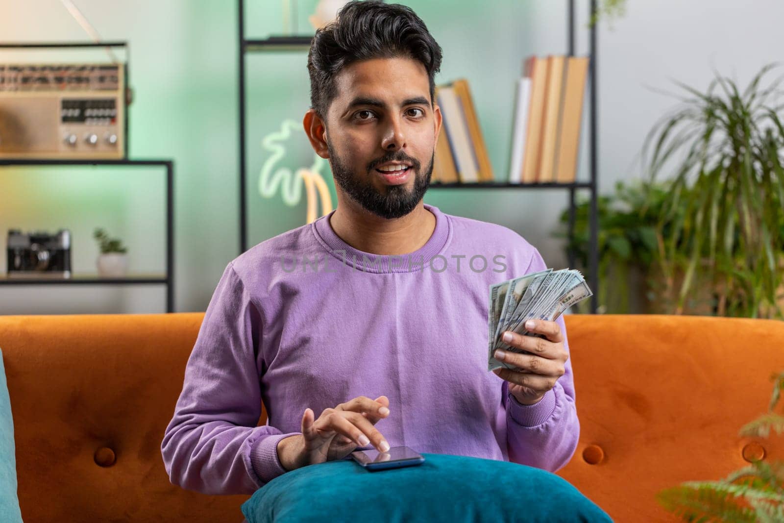 Rich indian man counting money cash and use calculator, calculate domestic income earnings at home by efuror