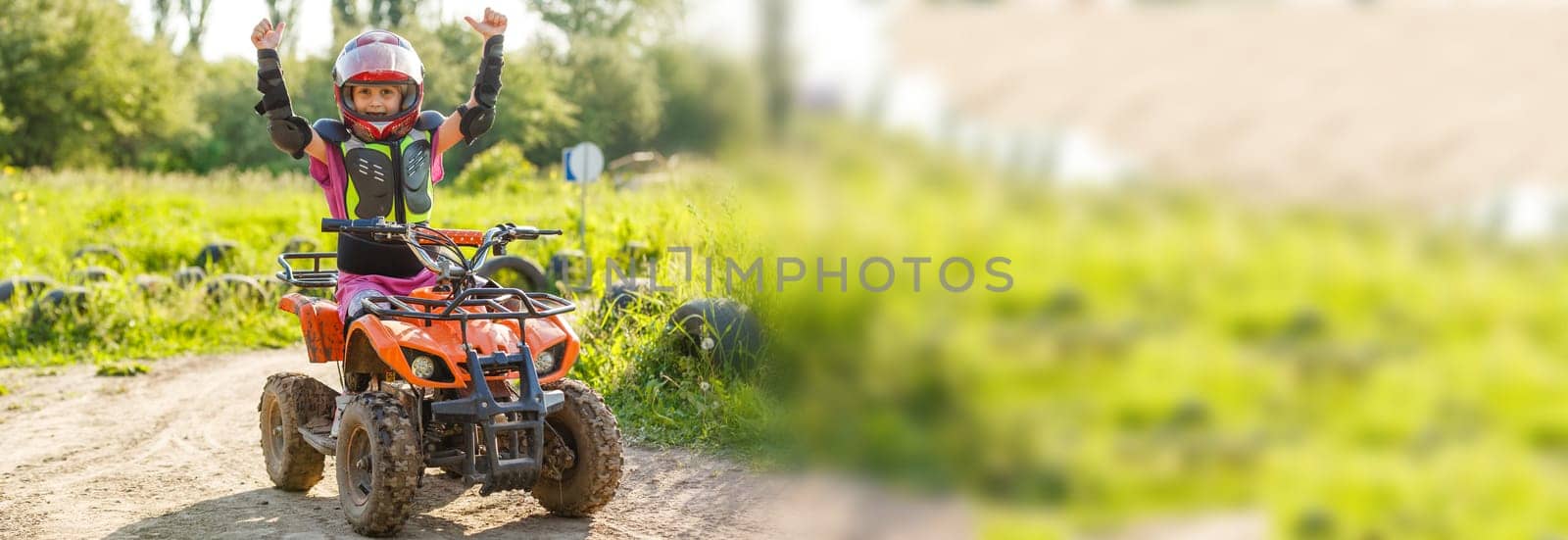 The little girl rides a quad bike. A mini quad bike is a cool girl in a helmet and protective clothing. Electric quad bike electric car for children popularizes green technology