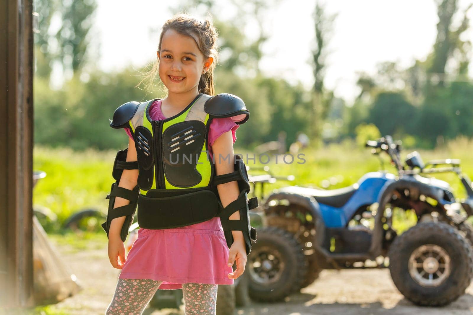 Happy little girl playing on road at the day time. He driving on quad bike in the park. Child having fun on the nature. Concept of happiness by Andelov13