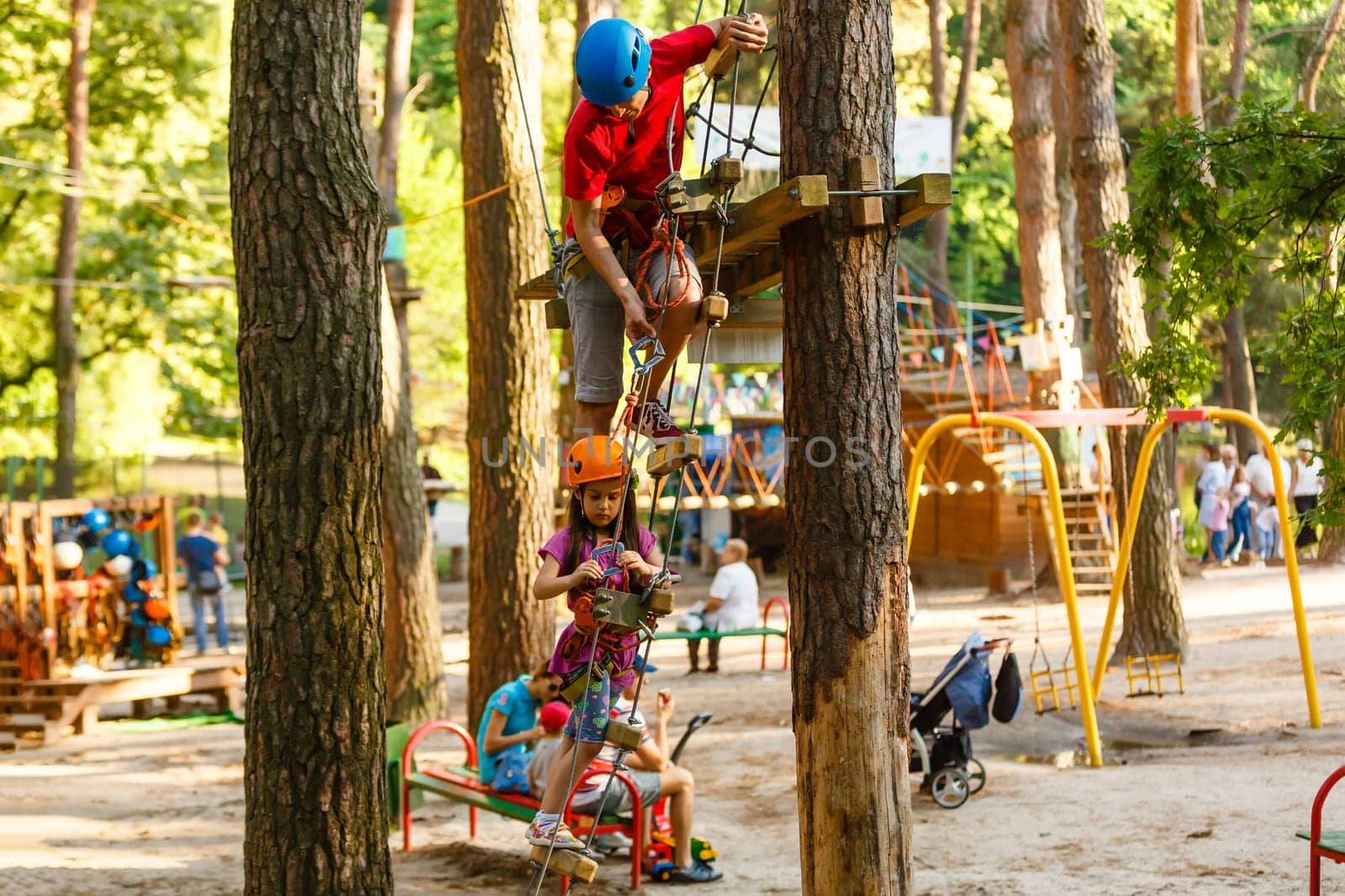 Young father helping his little daughter in the rope park