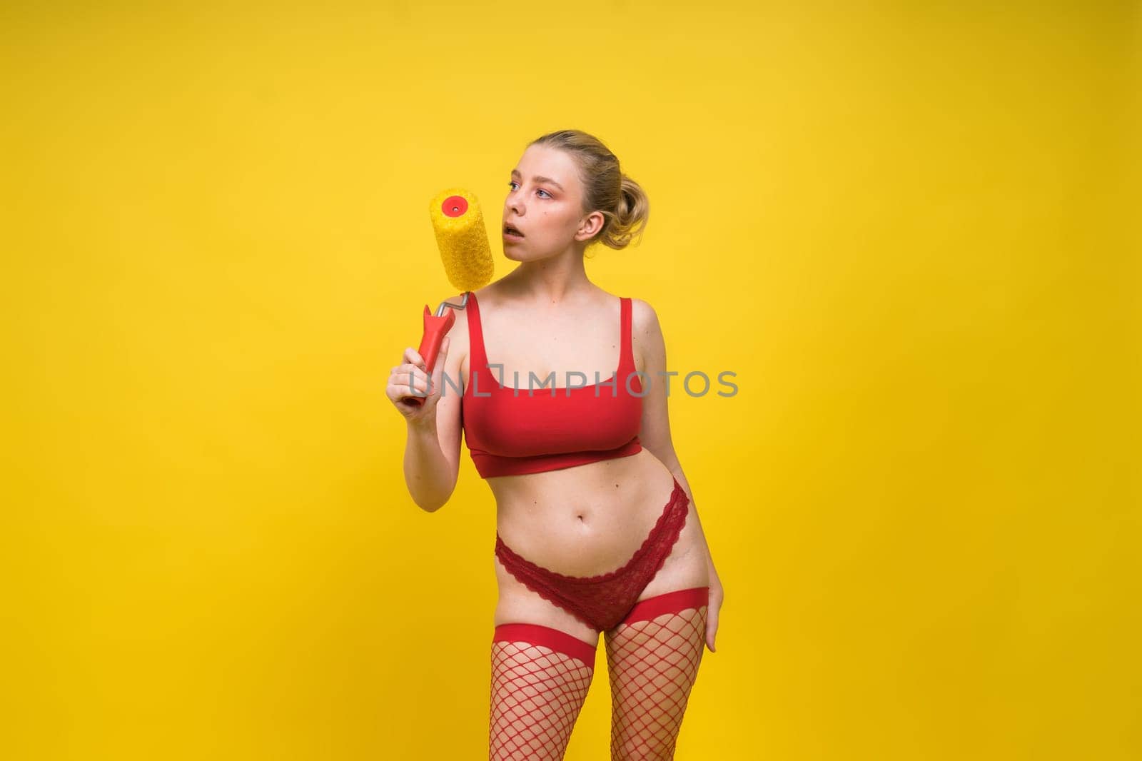 Young classic pin-up woman painting wall with paint roller by Zelenin