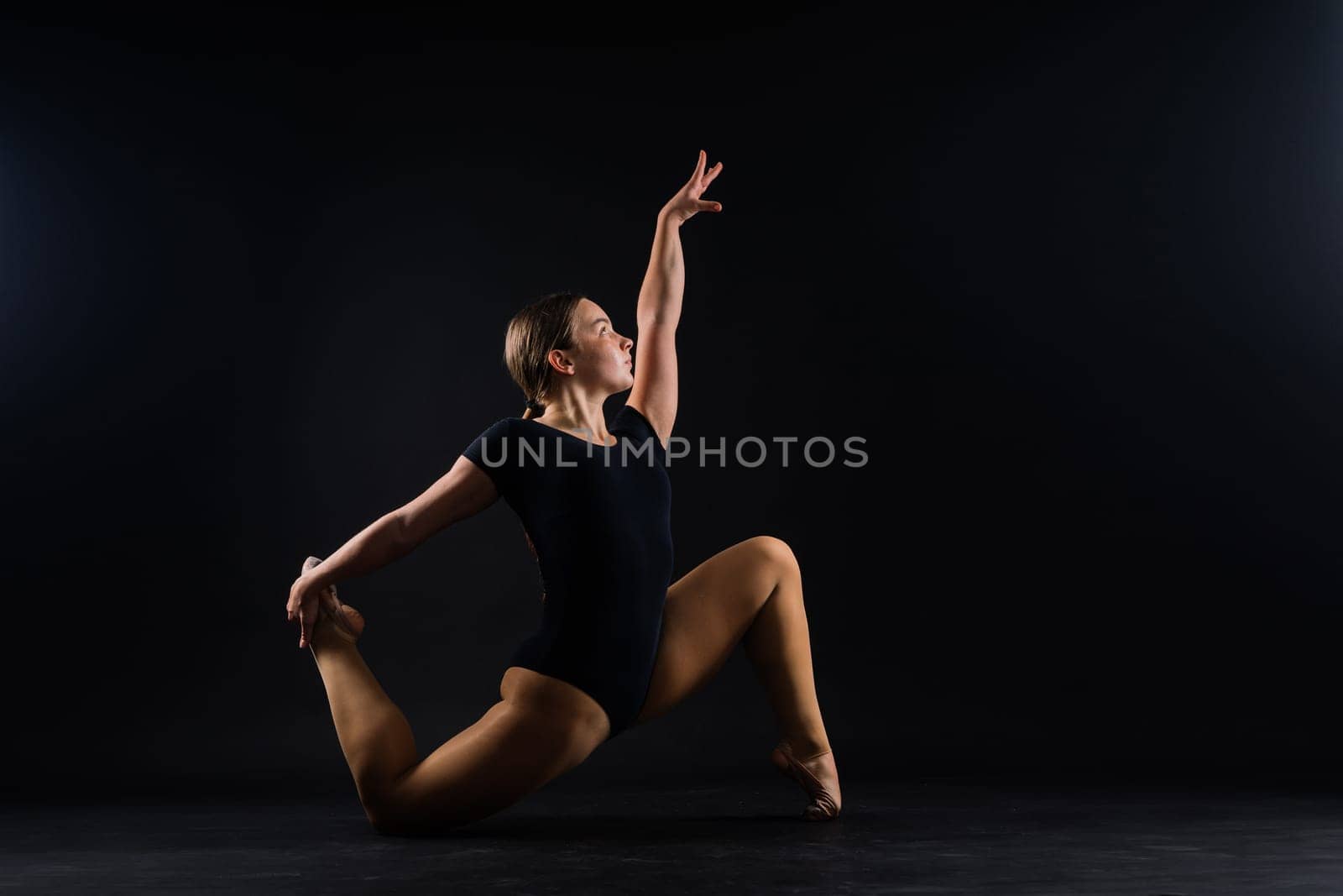 Flexible girl, rhythmic gymnastic artist jumping on white dark background. Grace in motion, action.