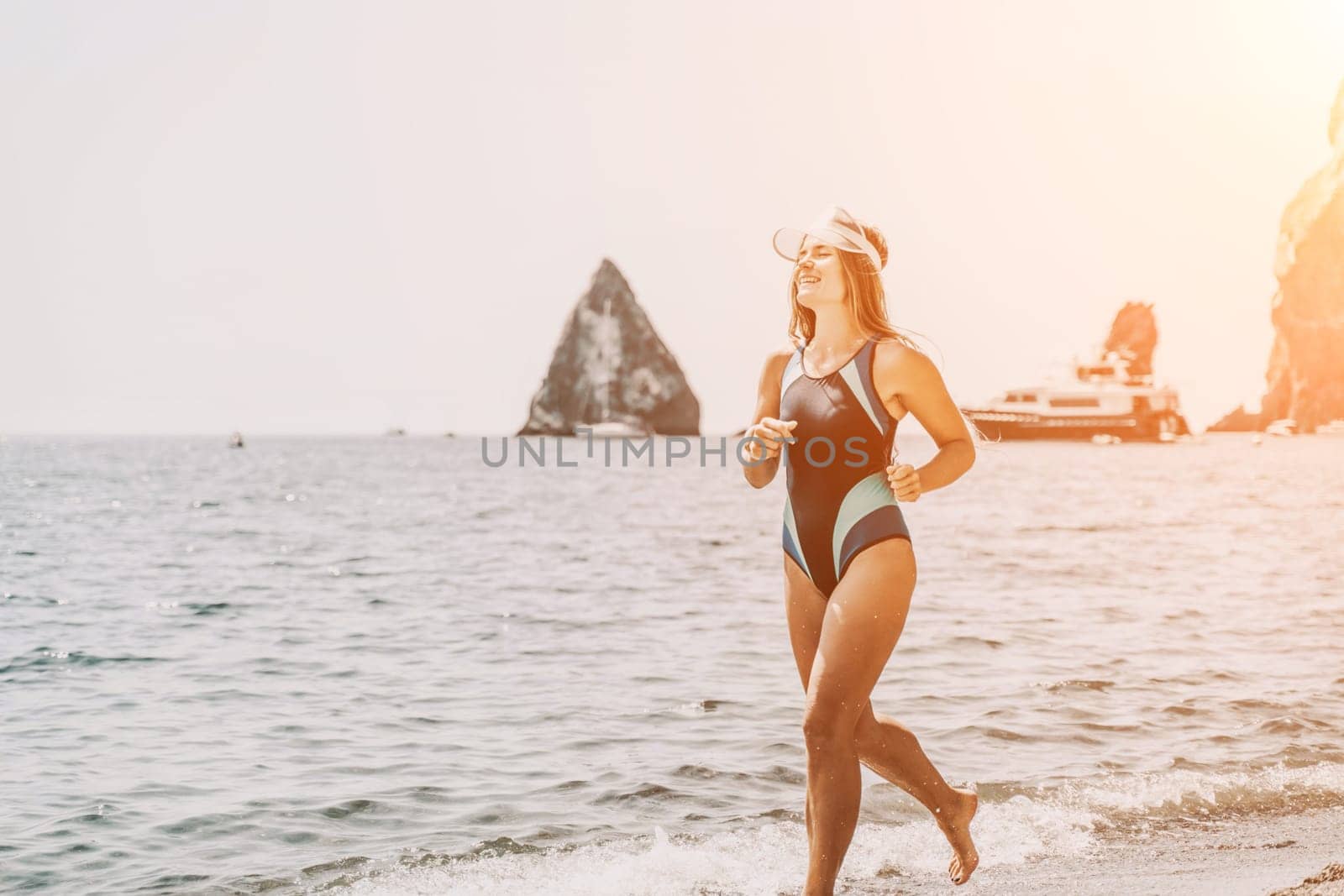 Woman travel summer sea. A happy tourist in a blue bikini enjoying the scenic view of the sea and volcanic mountains while taking pictures to capture the memories of her travel adventure