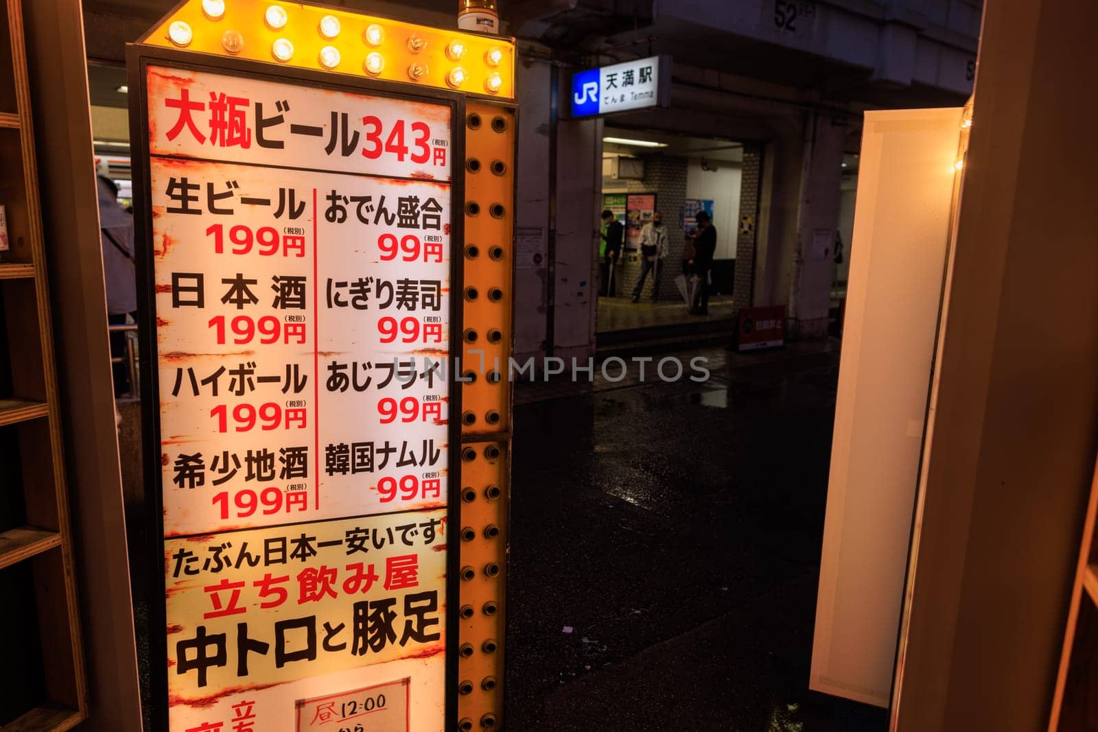 Osaka, Japan - April 29, 2023: Illuminated sign in Japanese with prices for bar food at restaurant by station . High quality photo