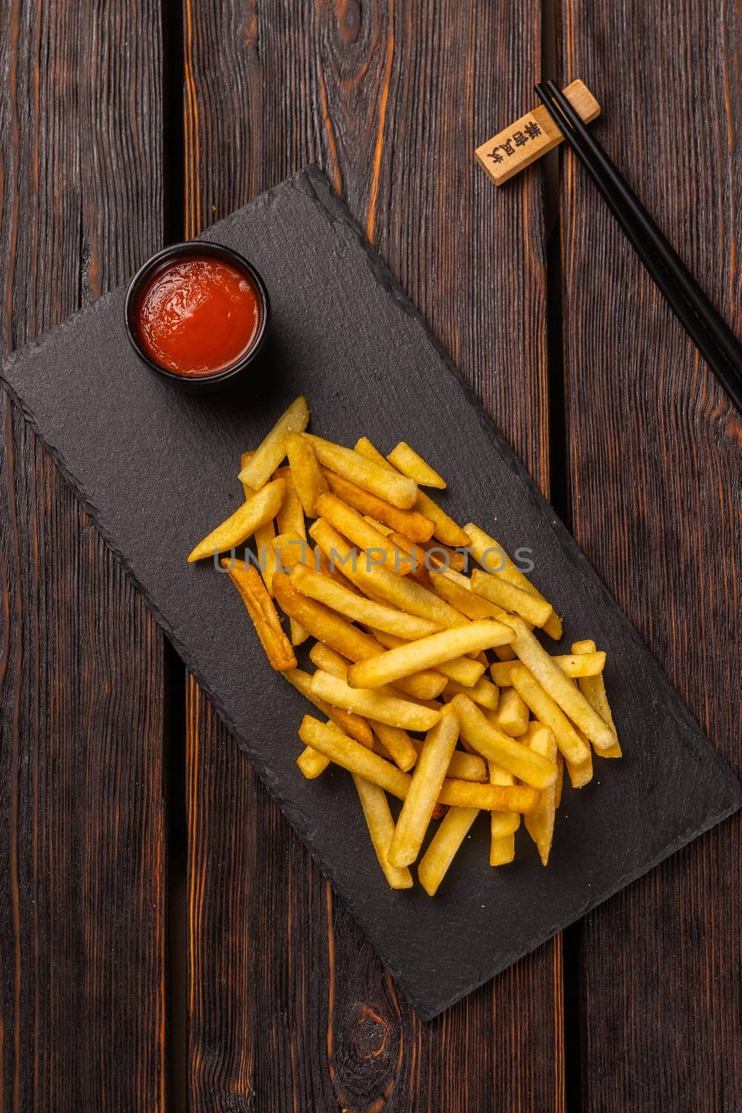 French fries with ketchup on dark background, top view