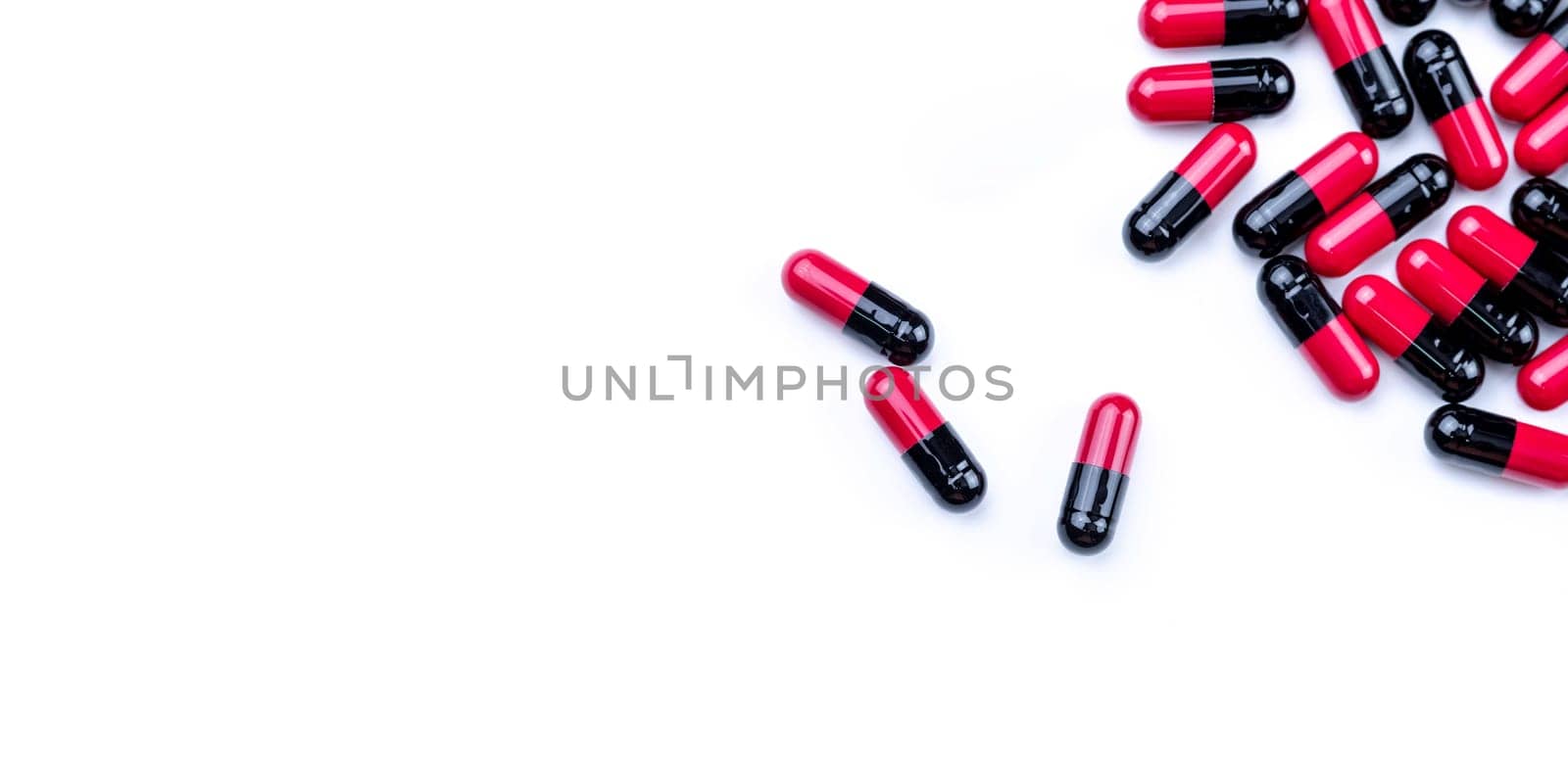 Top view red-black antibiotic capsule pills on white background. Prescription drug. Antibiotic drug. Pharmaceutical industry. Antimicrobial pills for treatment infections. Healthcare and medicine.