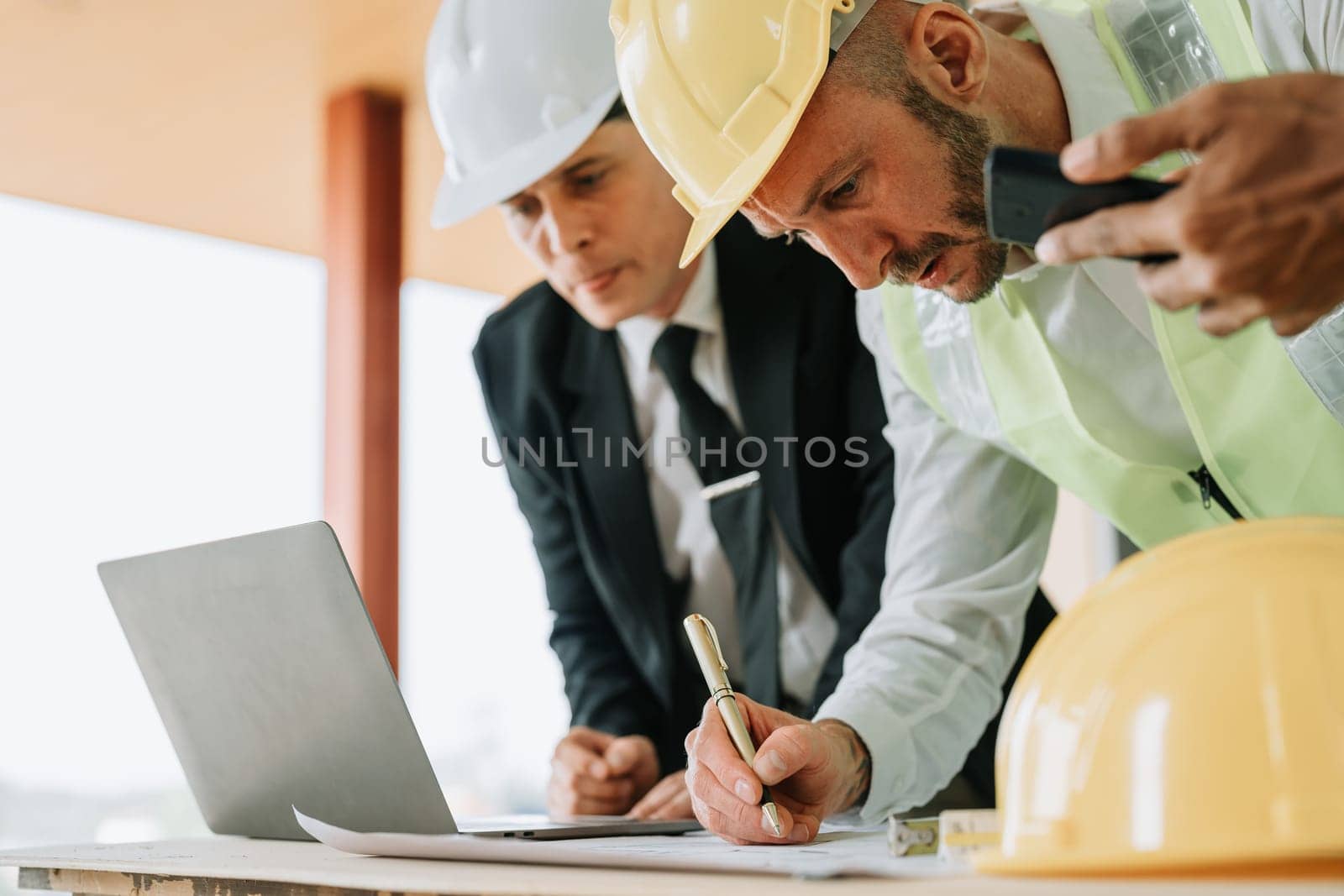 multi ethnic engineer brainstorming and measuring for cost estimating on blueprint and floor plan drawings about design architectural and engineering for houses and buildings.