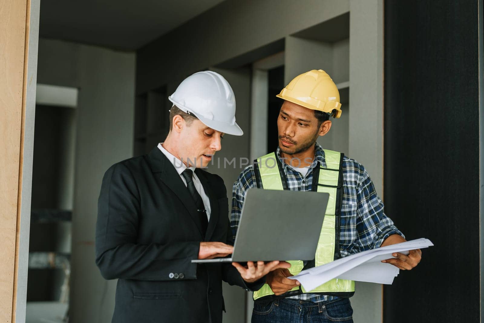 multi ethnic engineer brainstorming and measuring for cost estimating on blueprint and floor plan drawings about design architectural and engineering for houses and buildings.