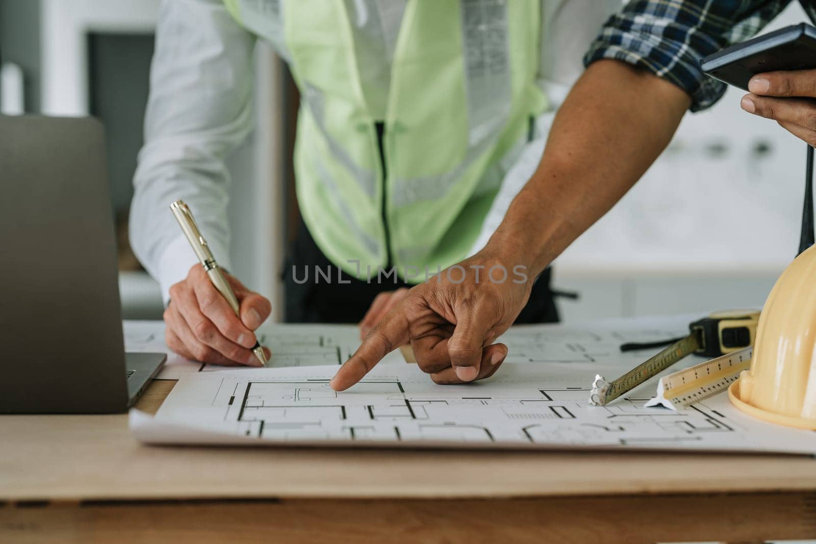 multi ethnic engineer brainstorming and measuring for cost estimating on paperworks and floor plan drawings about design architectural and engineering for houses and buildings.
