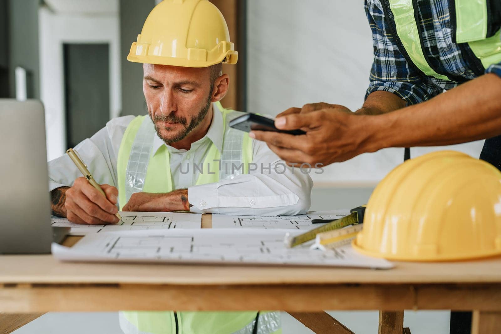 multi ethnic engineer brainstorming and measuring for cost estimating on paperworks and floor plan drawings about design architectural and engineering for houses and buildings by Manastrong