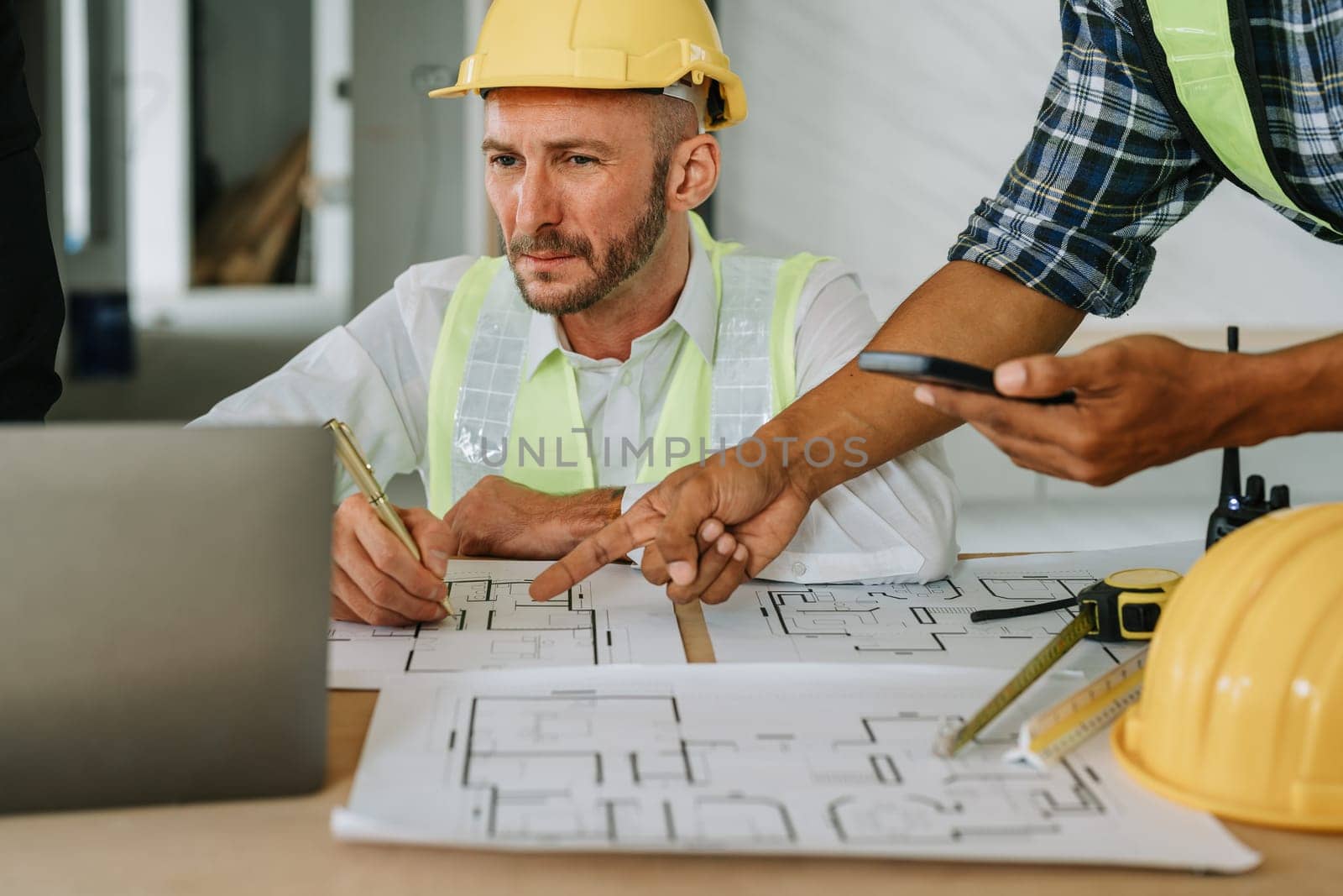 multi ethnic engineer brainstorming and measuring for cost estimating on paperworks and floor plan drawings about design architectural and engineering for houses and buildings.