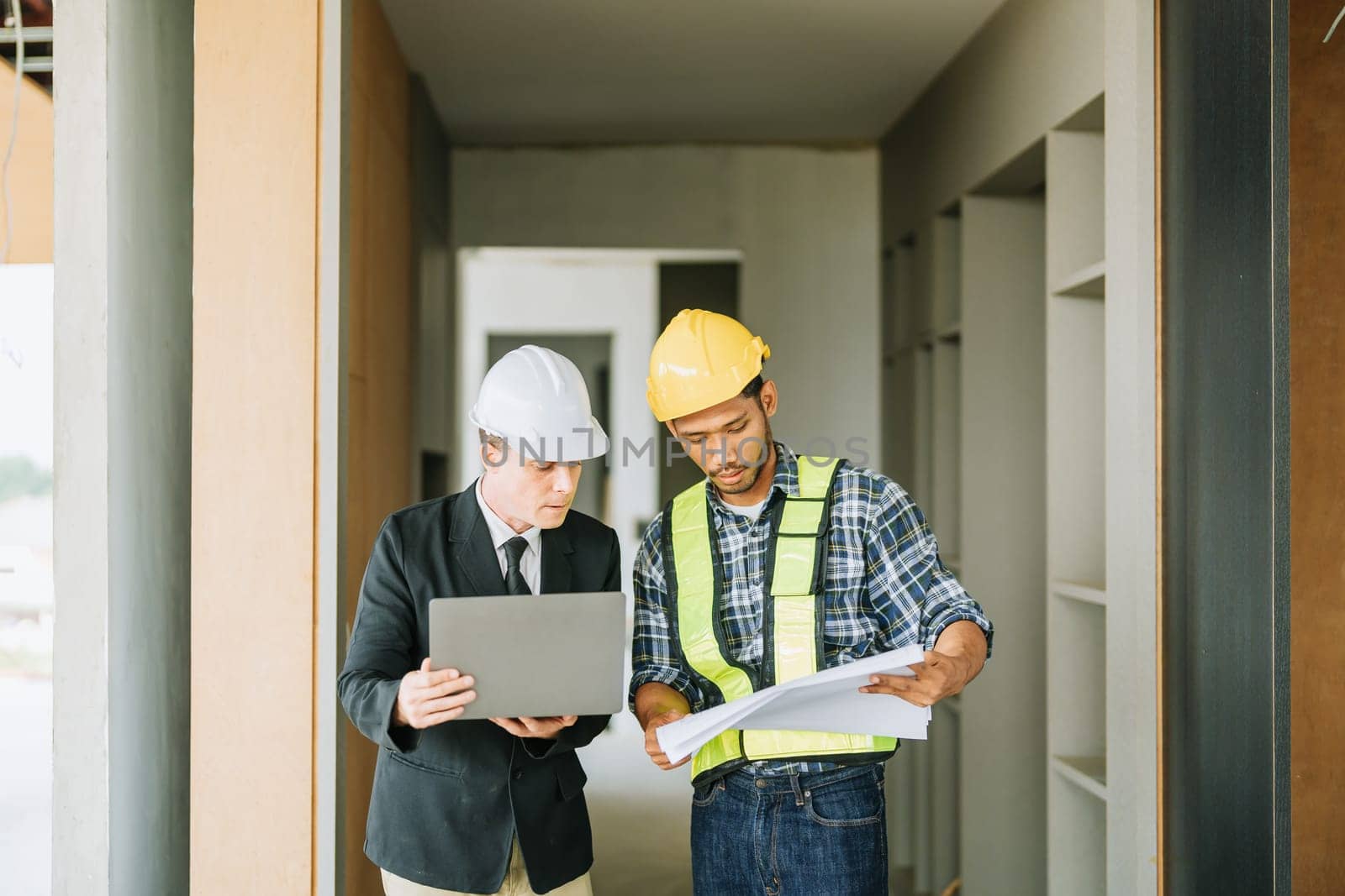 multi ethnic engineer brainstorming and measuring for cost estimating on blueprint and floor plan drawings about design architectural and engineering for houses and buildings.