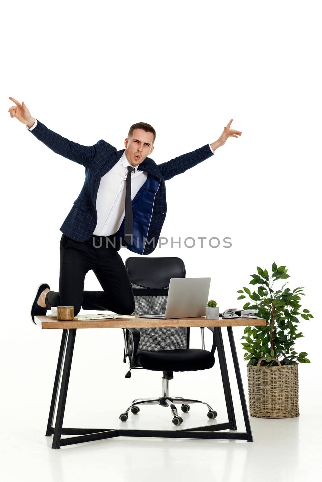 Satisfied young businessman gesturing emotionally and celebrating victory in the office