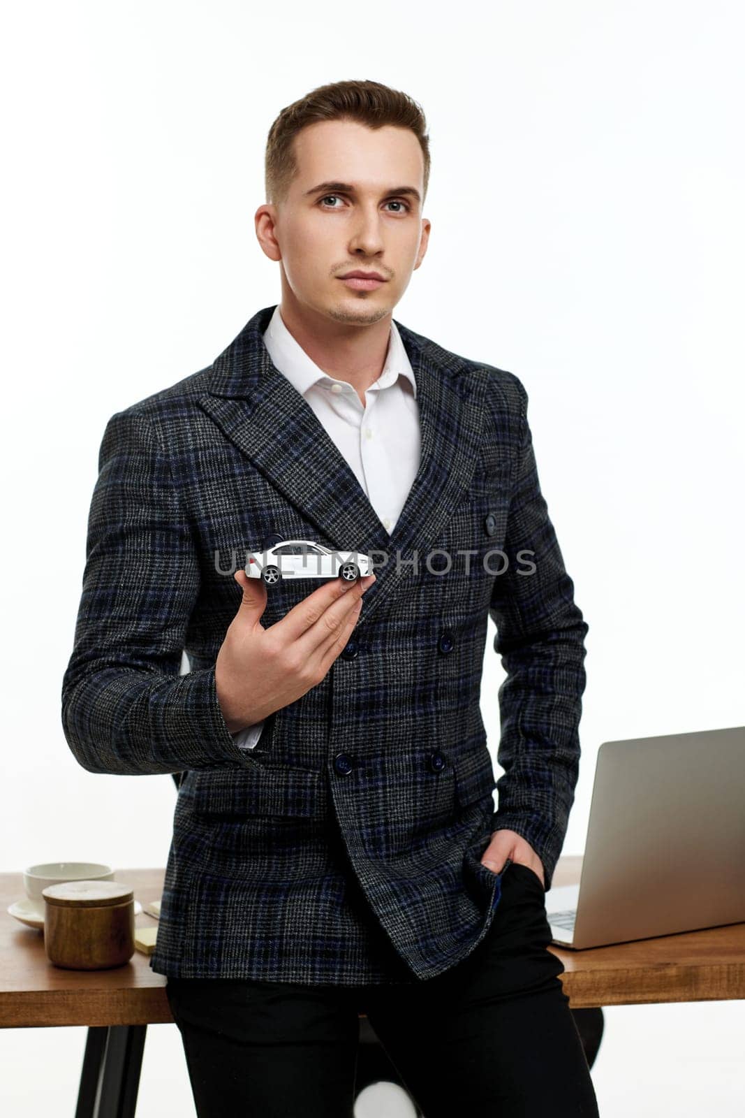 Successful caucasian businessman holding a toy car while standing at desk. Car dealerships offer car . Car insurance