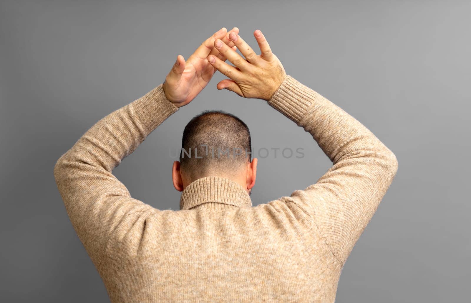 Half-bald man energetically patting his back, excited by the spectacle he has just witnessed. Isolated on gray background