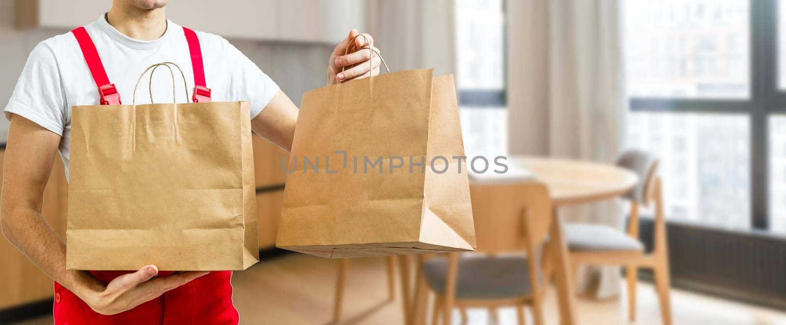 Young handsome man holding delivery paper bag.