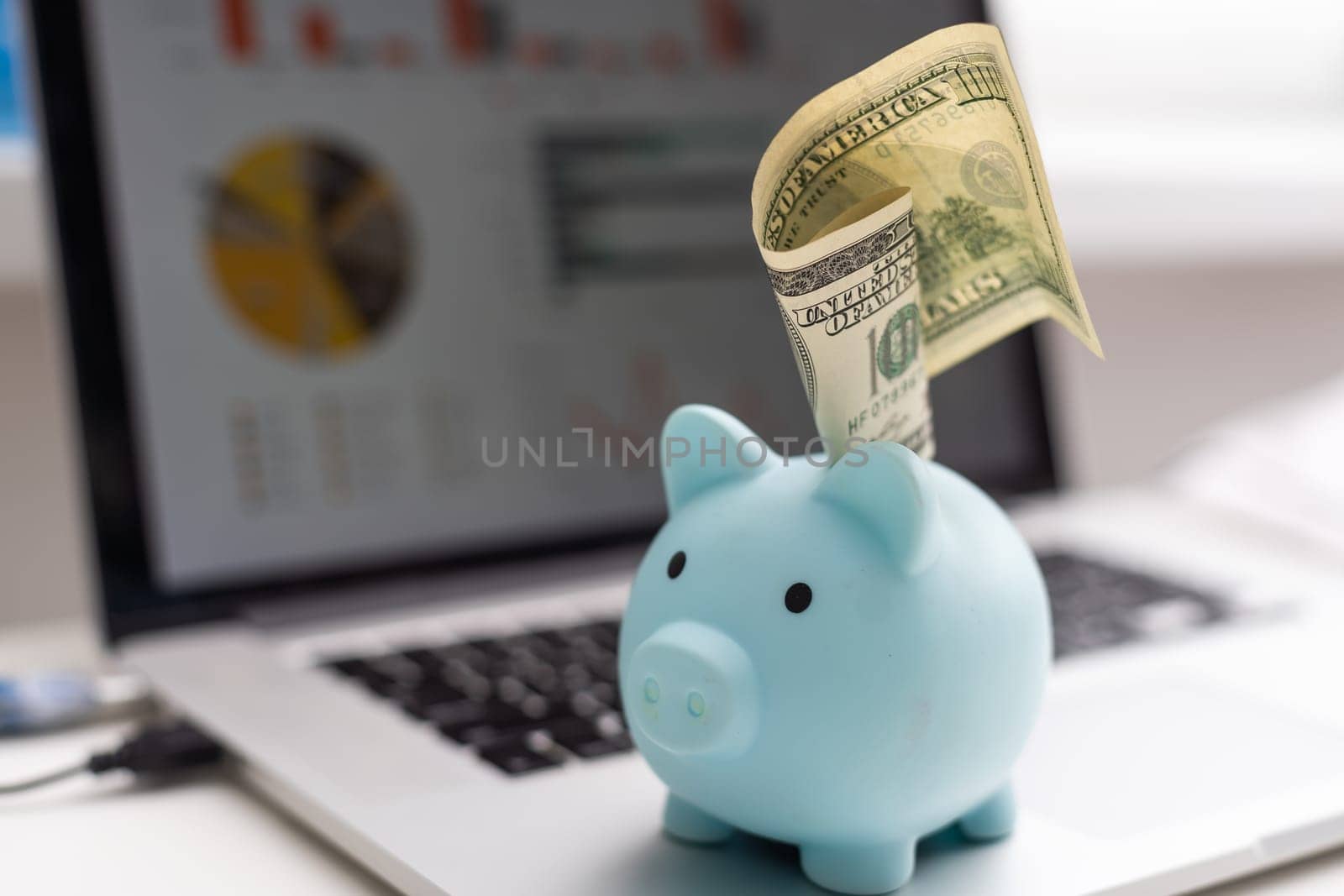 pink piggy bank sitting on a laptop displaying online savings on a white background
