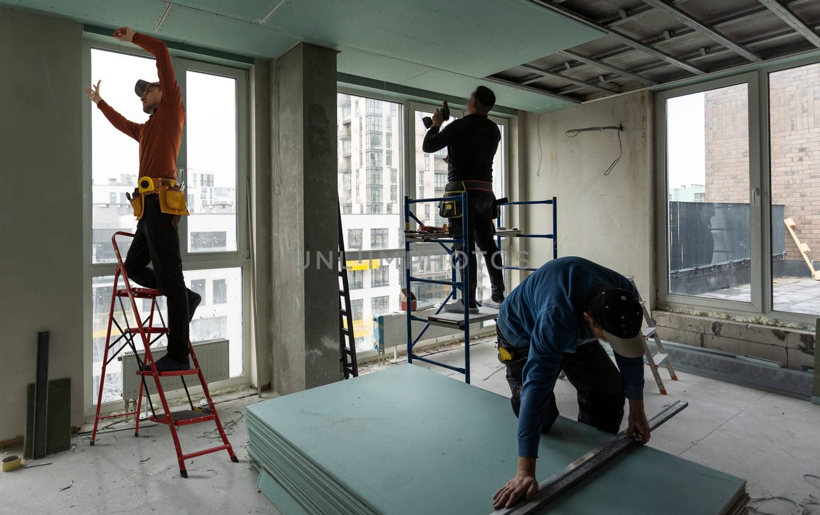 Worker stands on a ladder and make a ceiling.