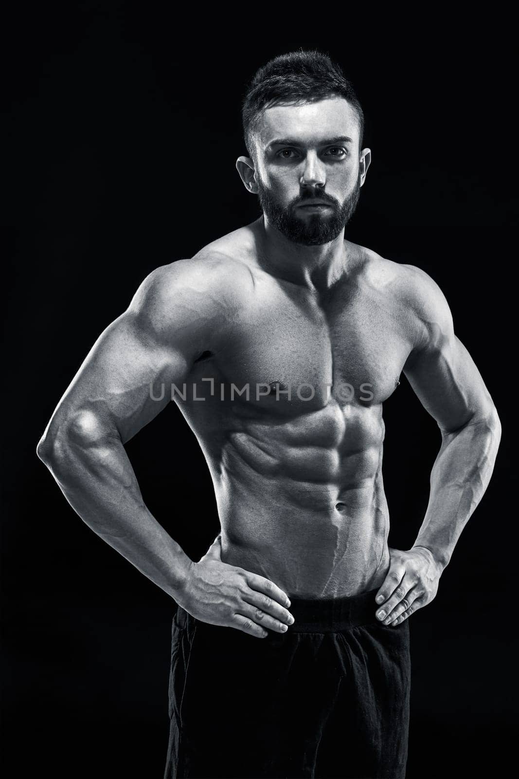 Muscular bodybuilder guy doing posing over black background. Black and white color