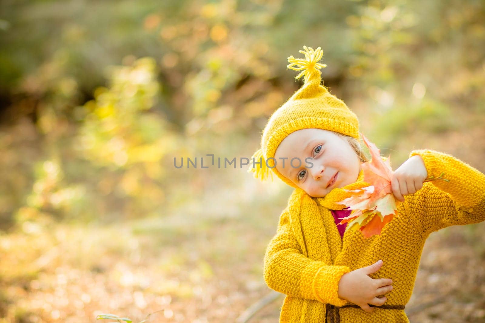 Young happy and smiling mom with her little daughter in arms hugging and kissing spending a weekend on a walk in autumn park.