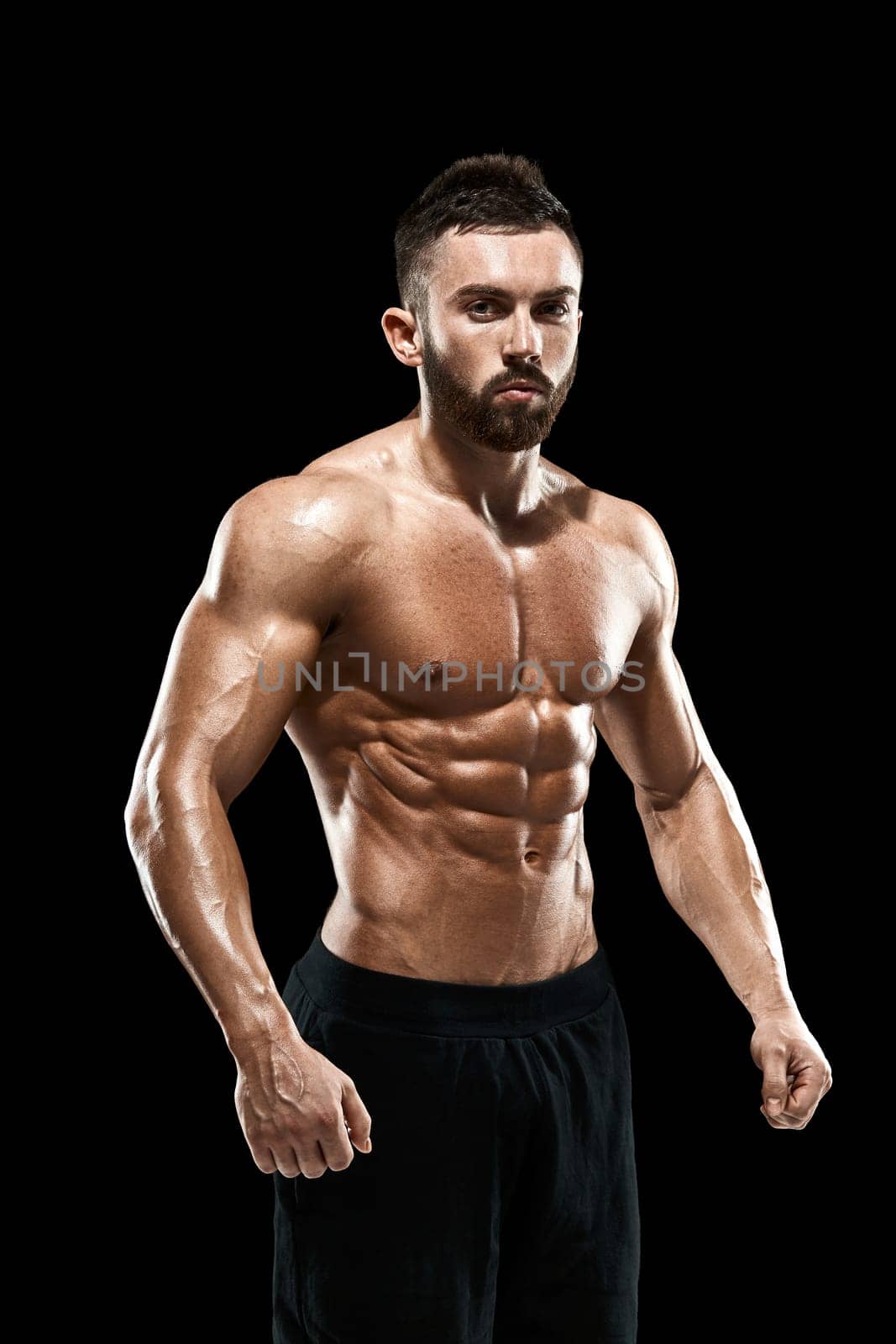Muscular bodybuilder guy doing posing over black background.