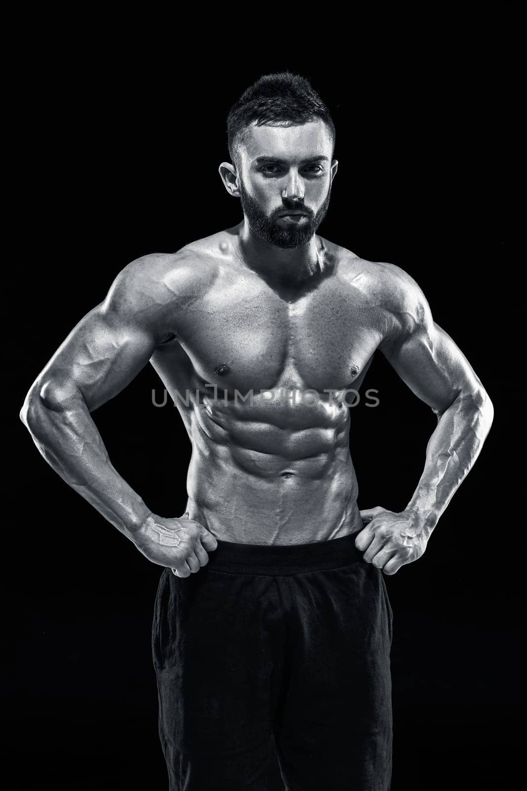 Muscular bodybuilder guy doing posing over black background.. Black and white color