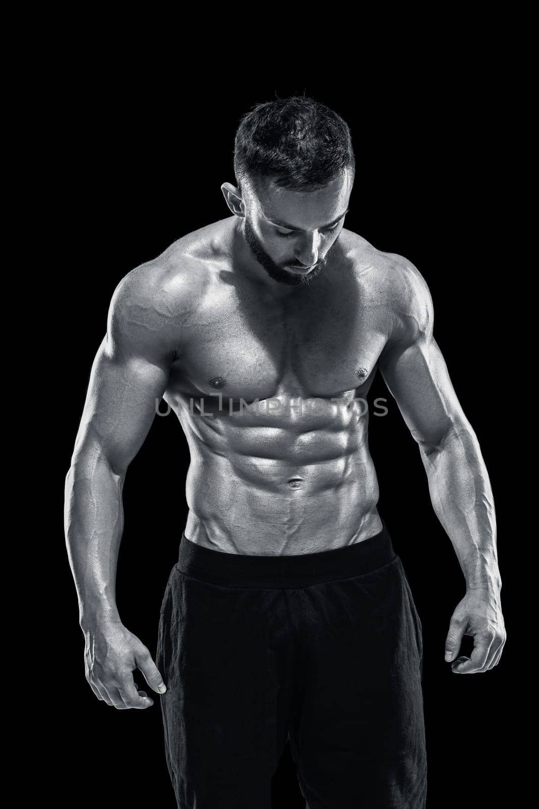 Muscular bodybuilder guy doing posing over black background.. Black and white color