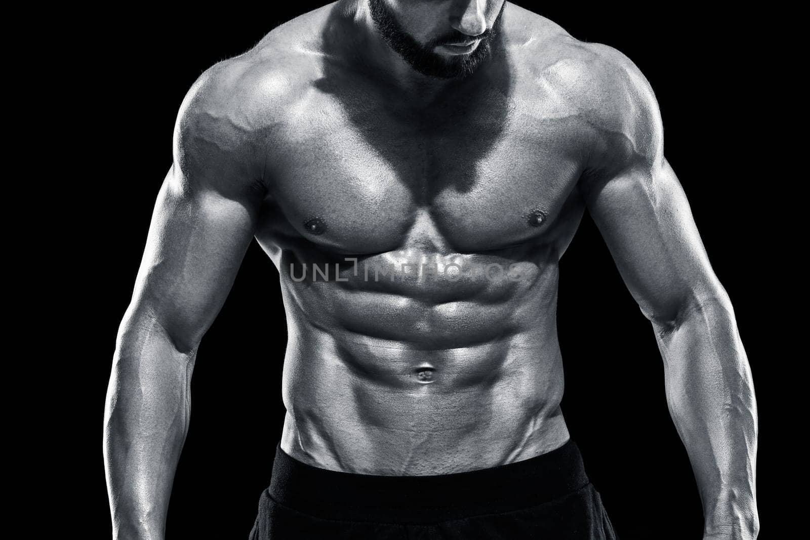Muscular bodybuilder guy doing posing over black background. Close up. Black and white color