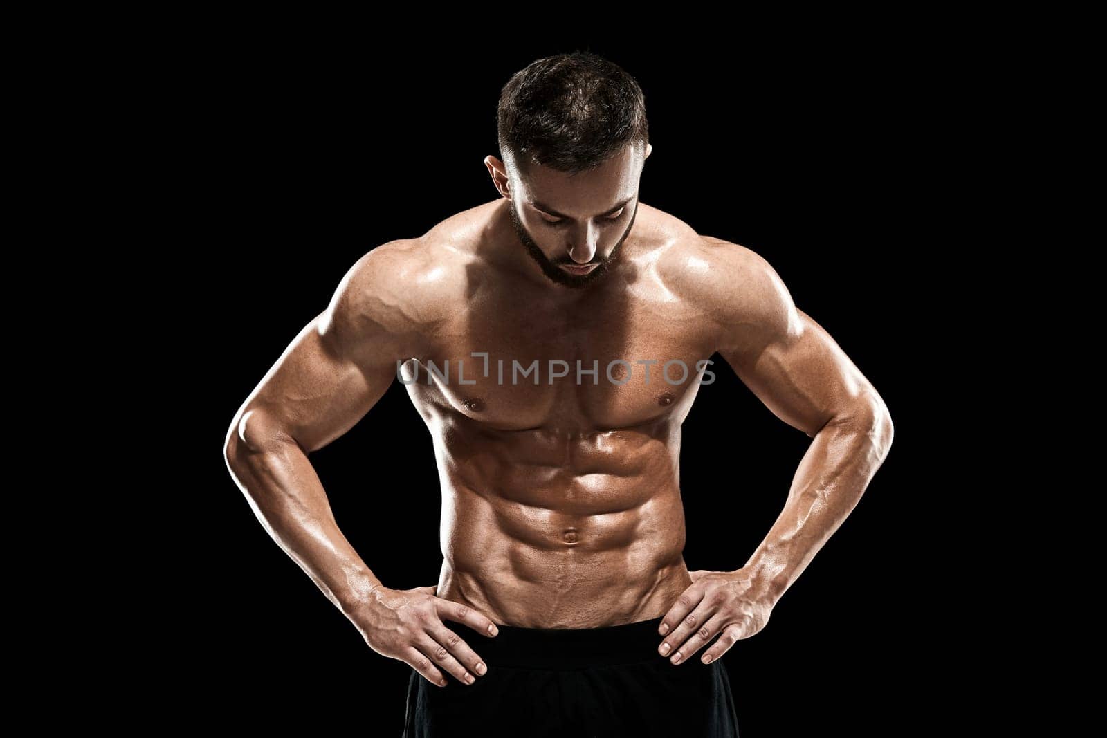 Muscular bodybuilder guy doing posing over black background.