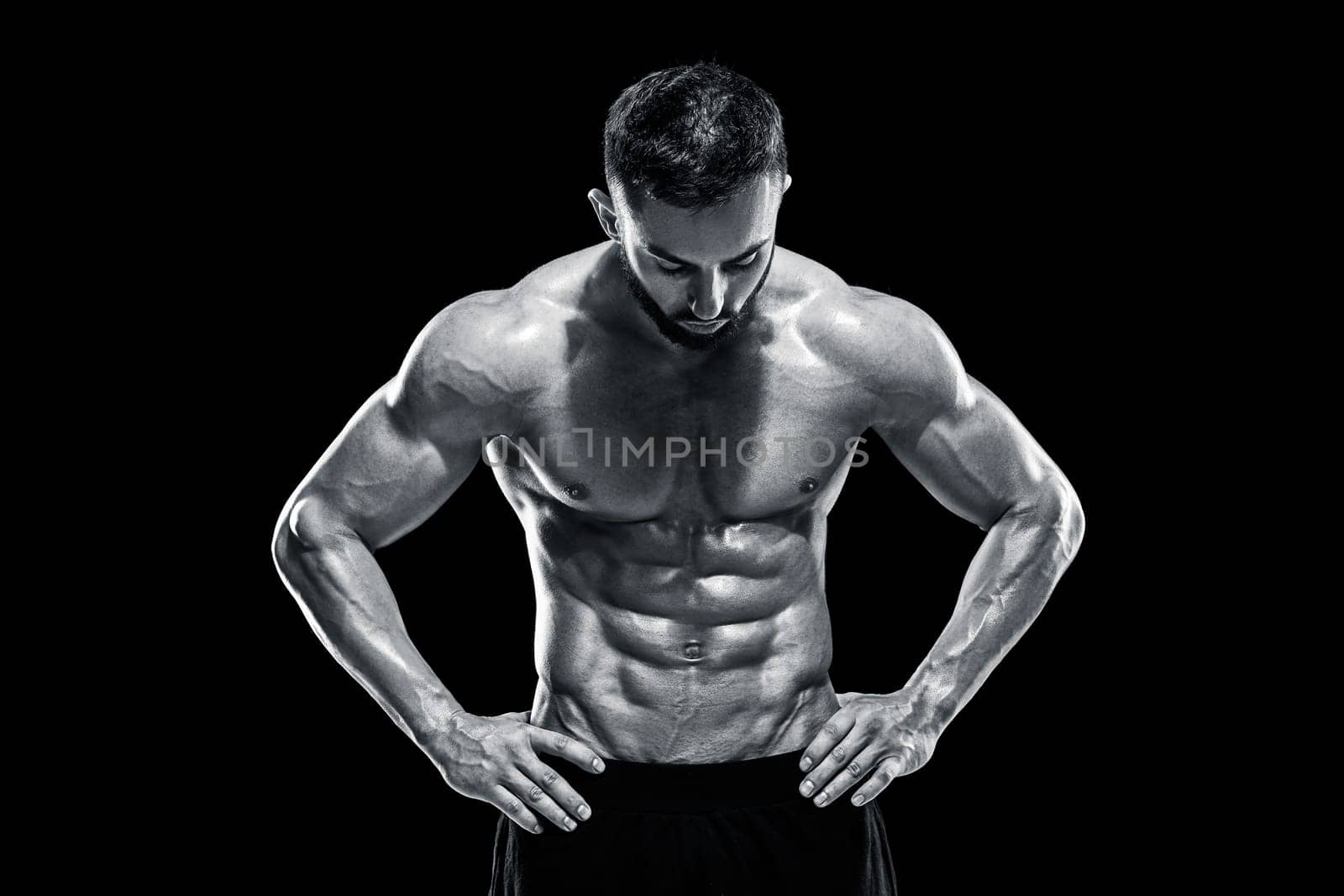 Muscular bodybuilder guy doing posing over black background.. Black and white color