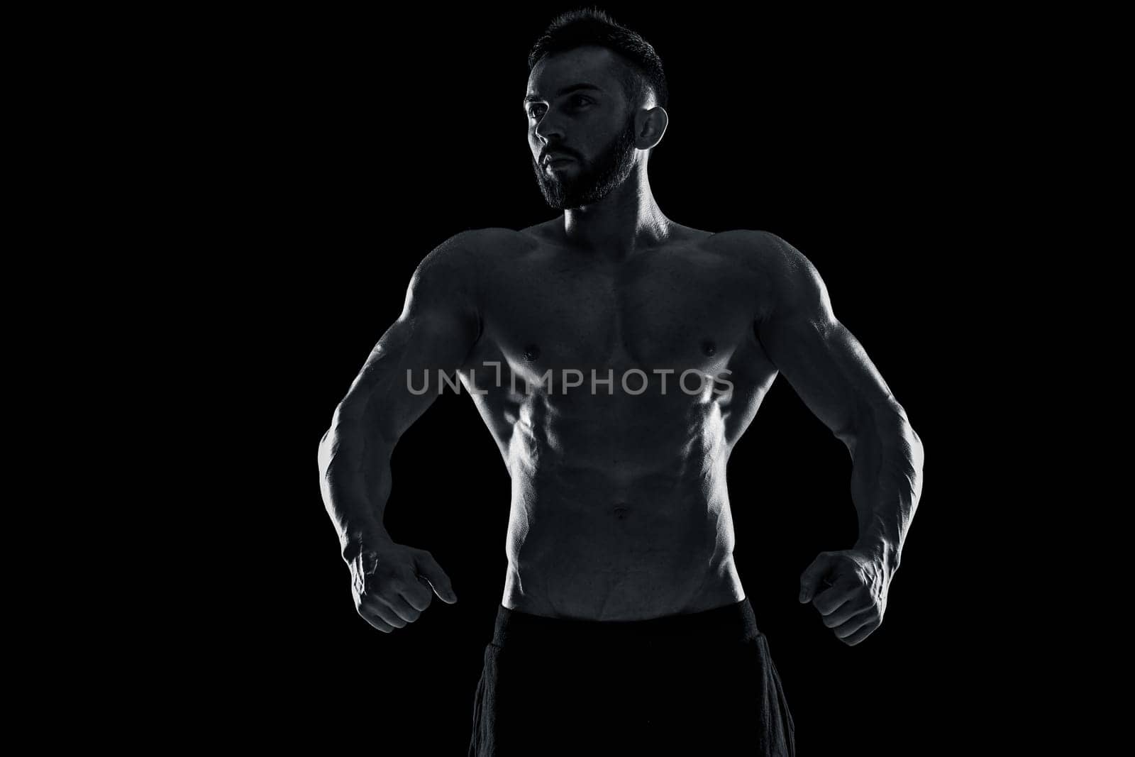 Muscular bodybuilder guy doing posing over black background. Black and white color