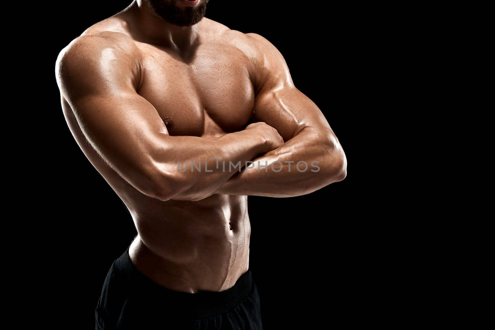 Muscular bodybuilder guy doing posing over black background. Close up