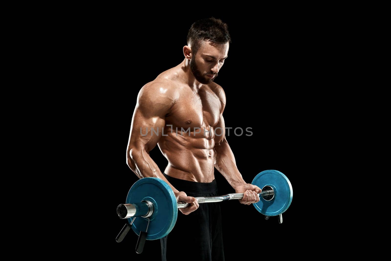 Close up of young muscular man lifting weights over dark background