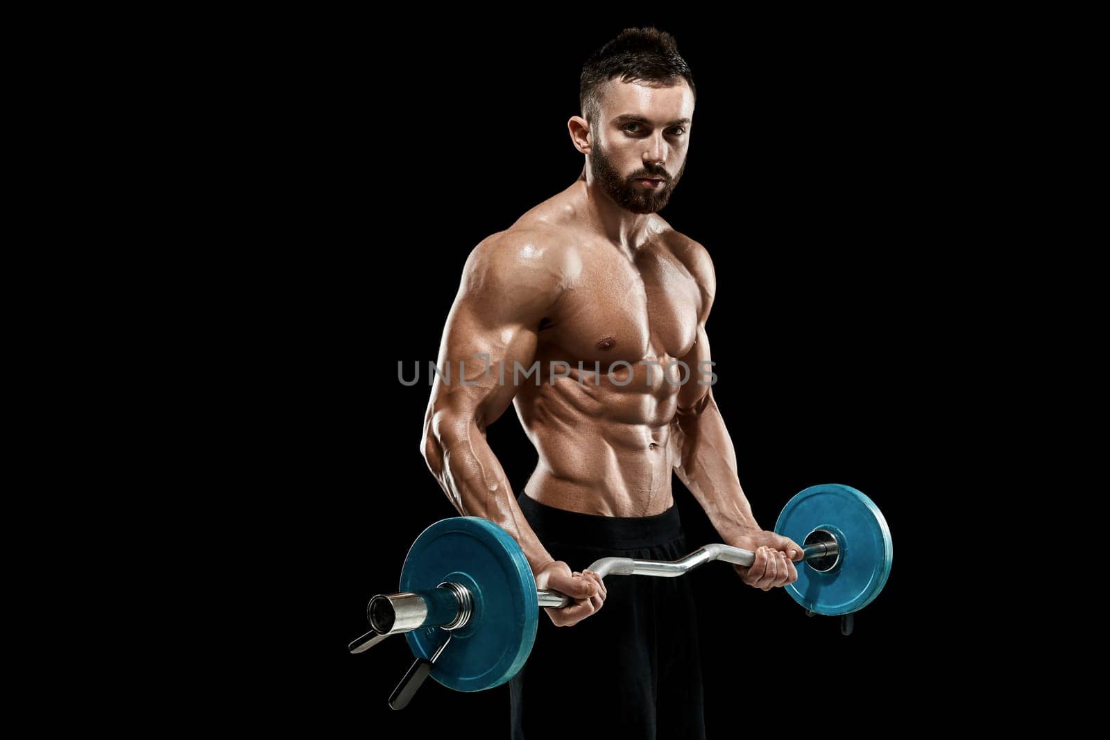 Close up of young muscular man lifting weights over dark background