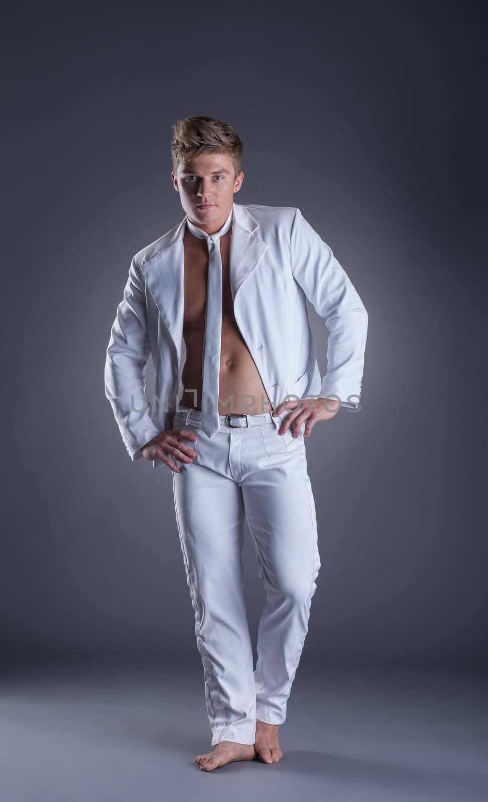 Sexy muscular dancer posing in studio, on gray background