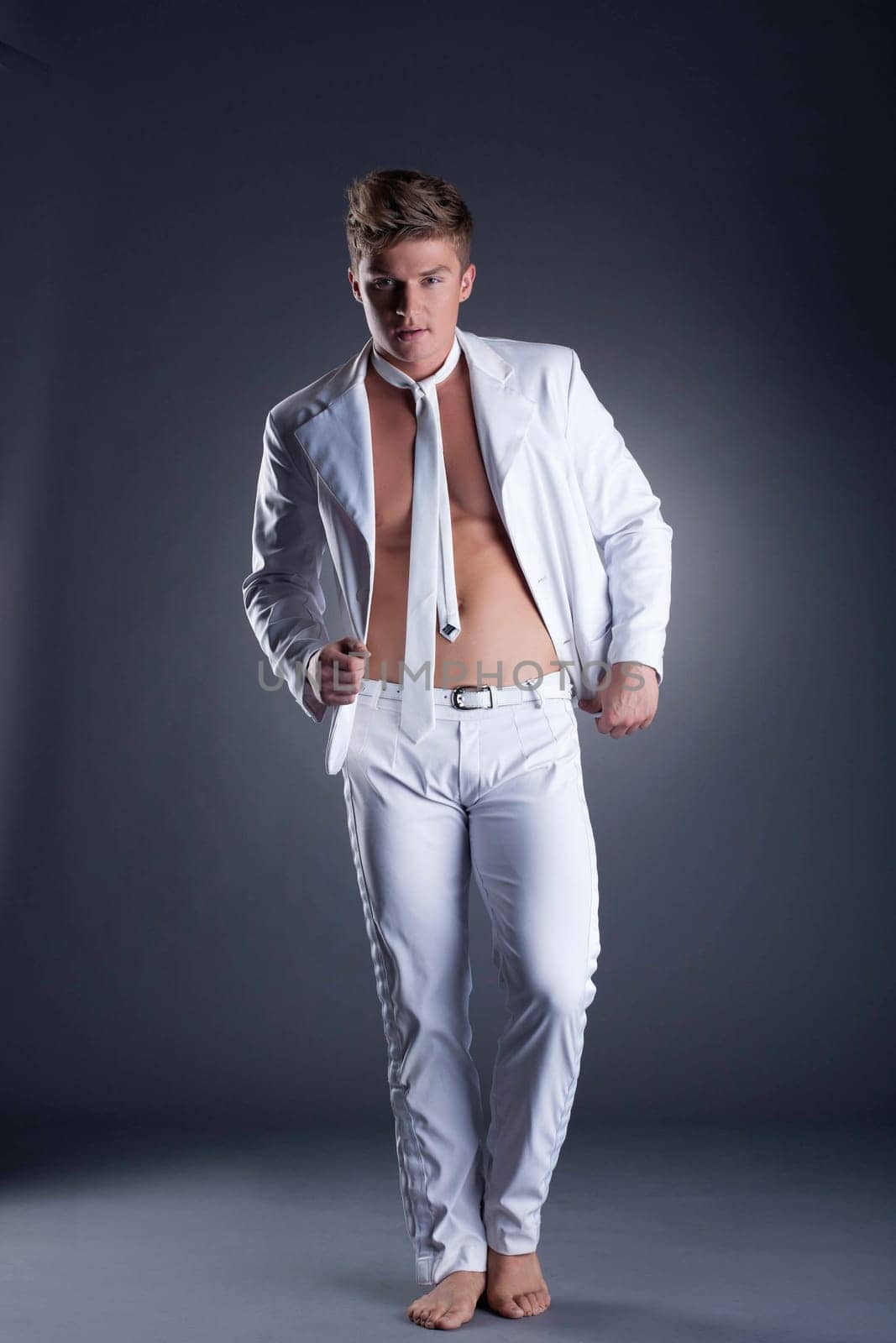 Image of handsome man posing in stylish white suit on gray background