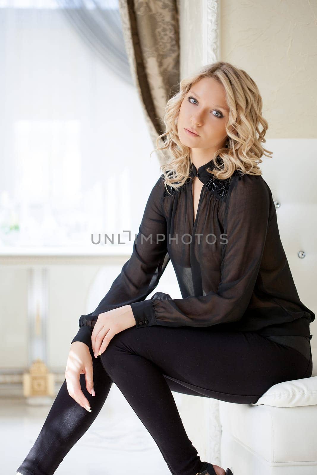 Portrait of young elegant blond posing on white sofa