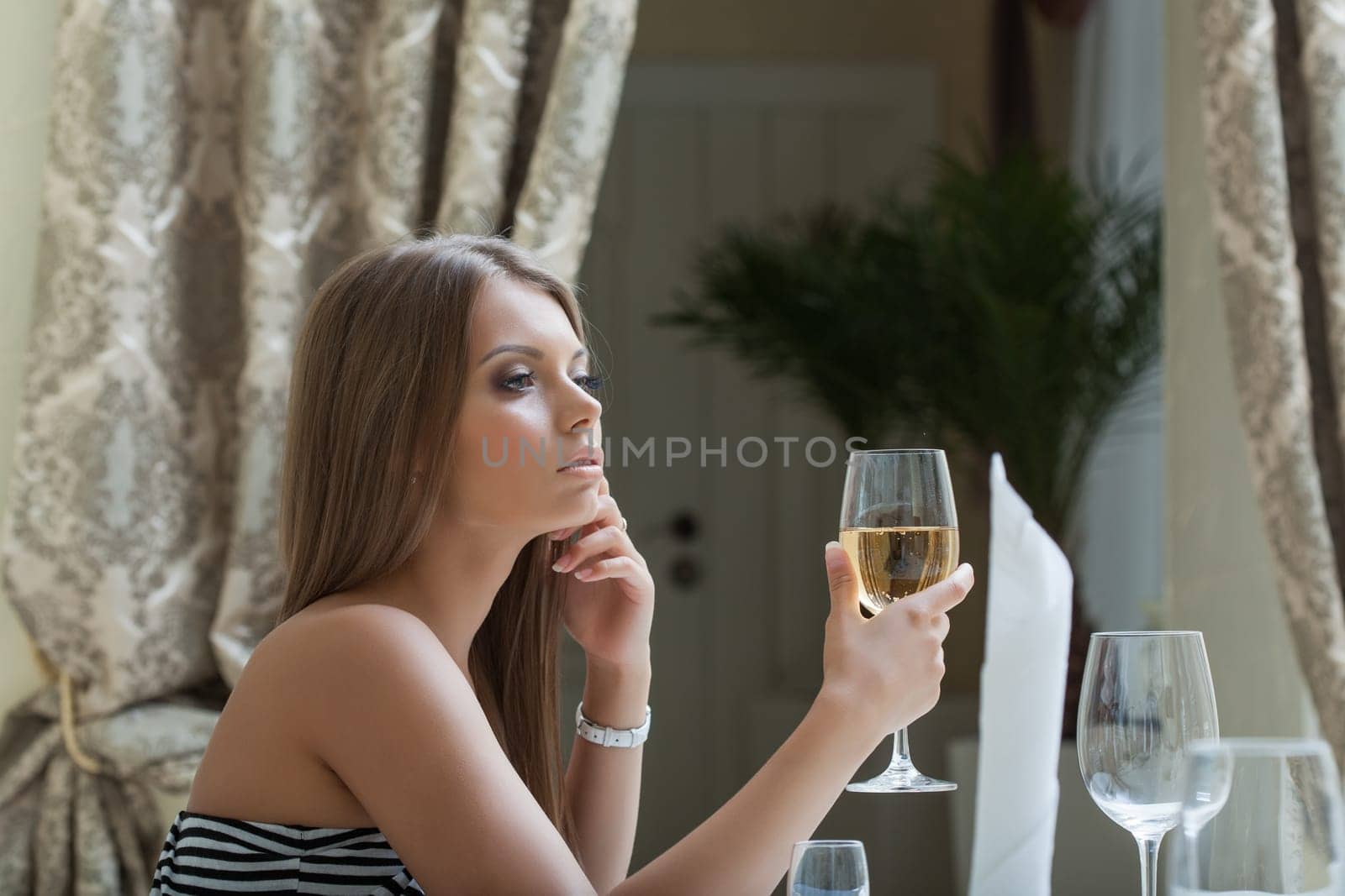 Portrait of thoughtful pretty woman posing with glass of wine