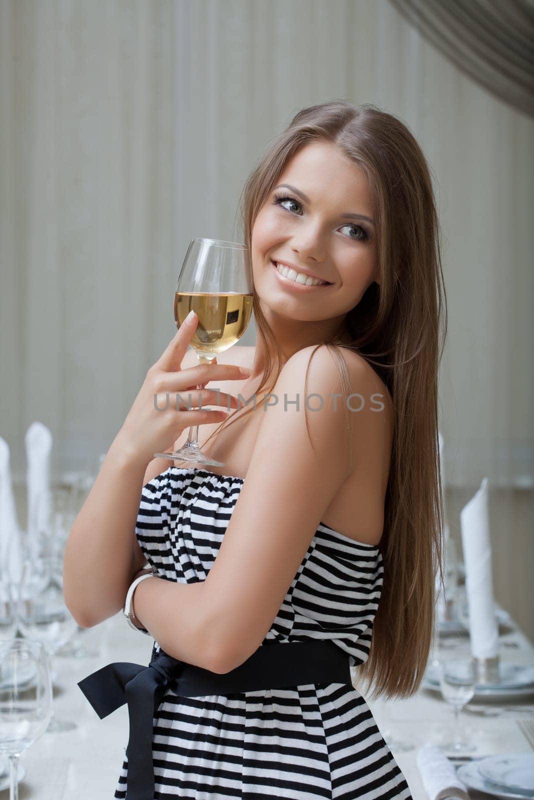 Portrait of charming smiling girl posing with glass of wine